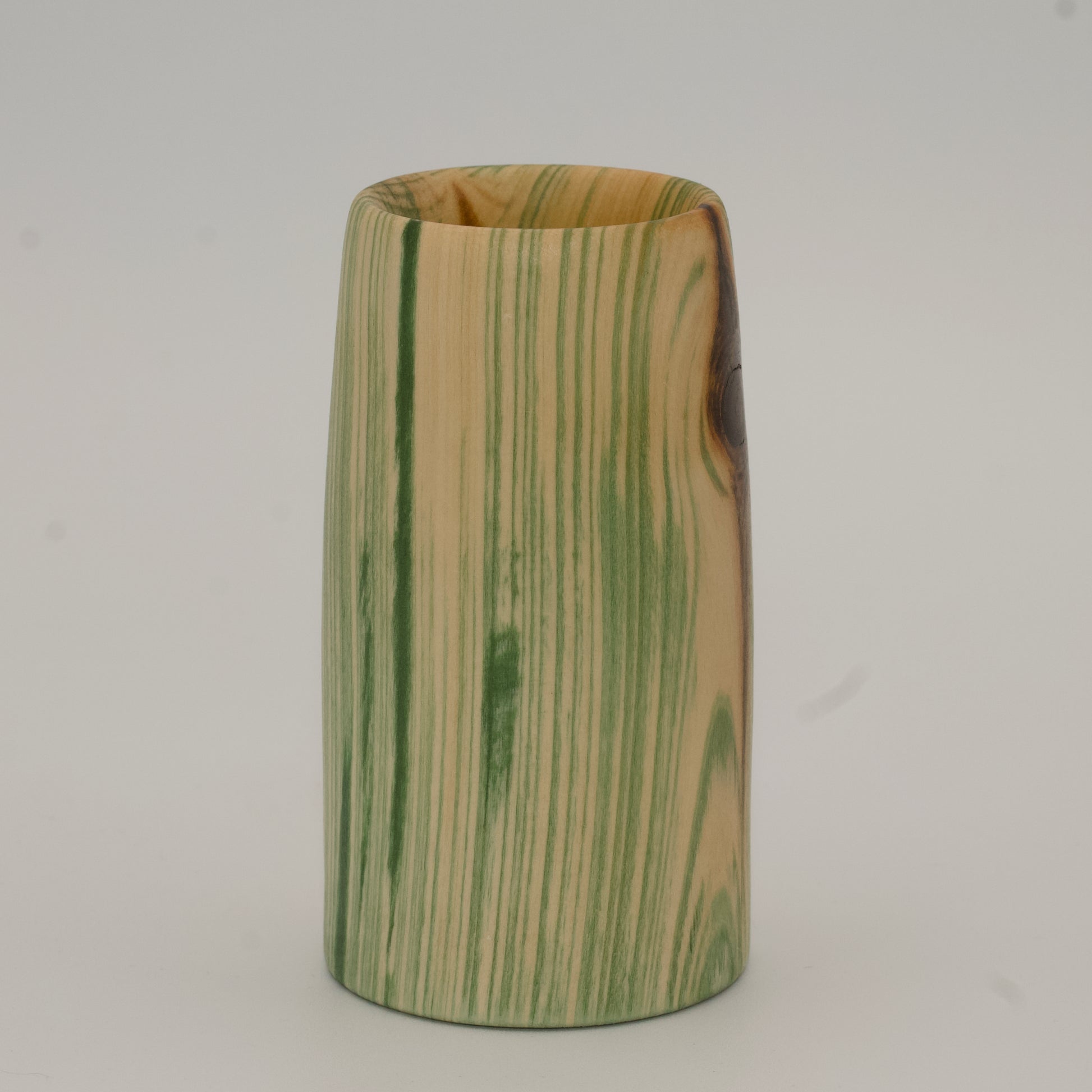 Wooden cup with green and brown marbled pattern on a wooden surface