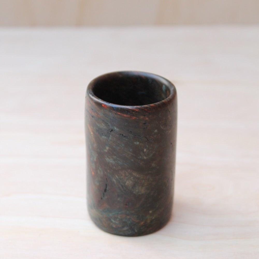 top view of multi-color wooden shot glass made of exotic burl wood on a light wooden background
