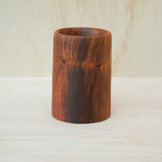 foodsafe, wooden shot glass with deep chocolate tones with light brown stripes on a light wooden background
