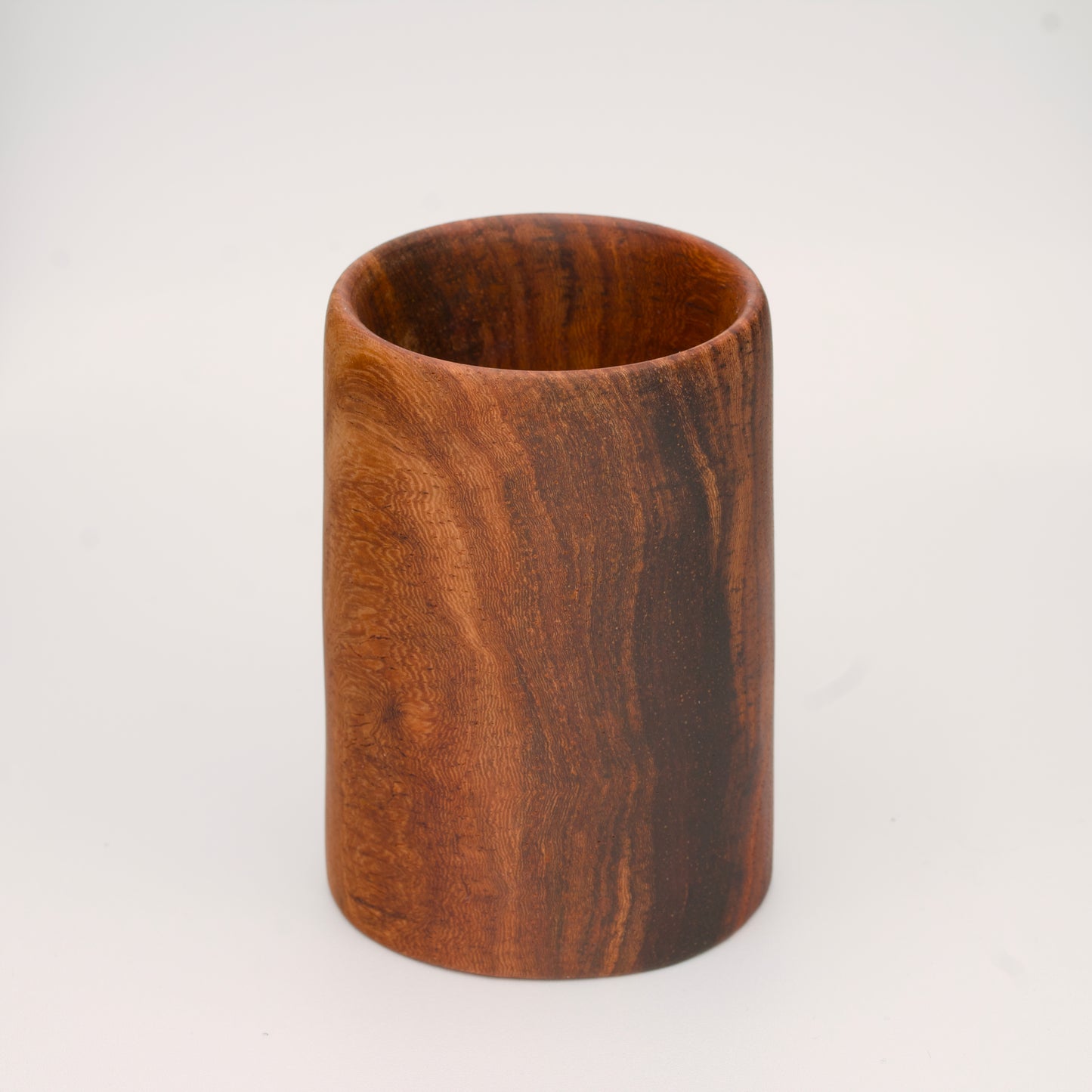 wooden shot glass with deep chocolate tones with light brown stripes on a white  background