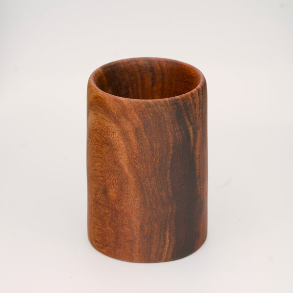 wooden shot glass with deep chocolate tones with light brown stripes on a white  background