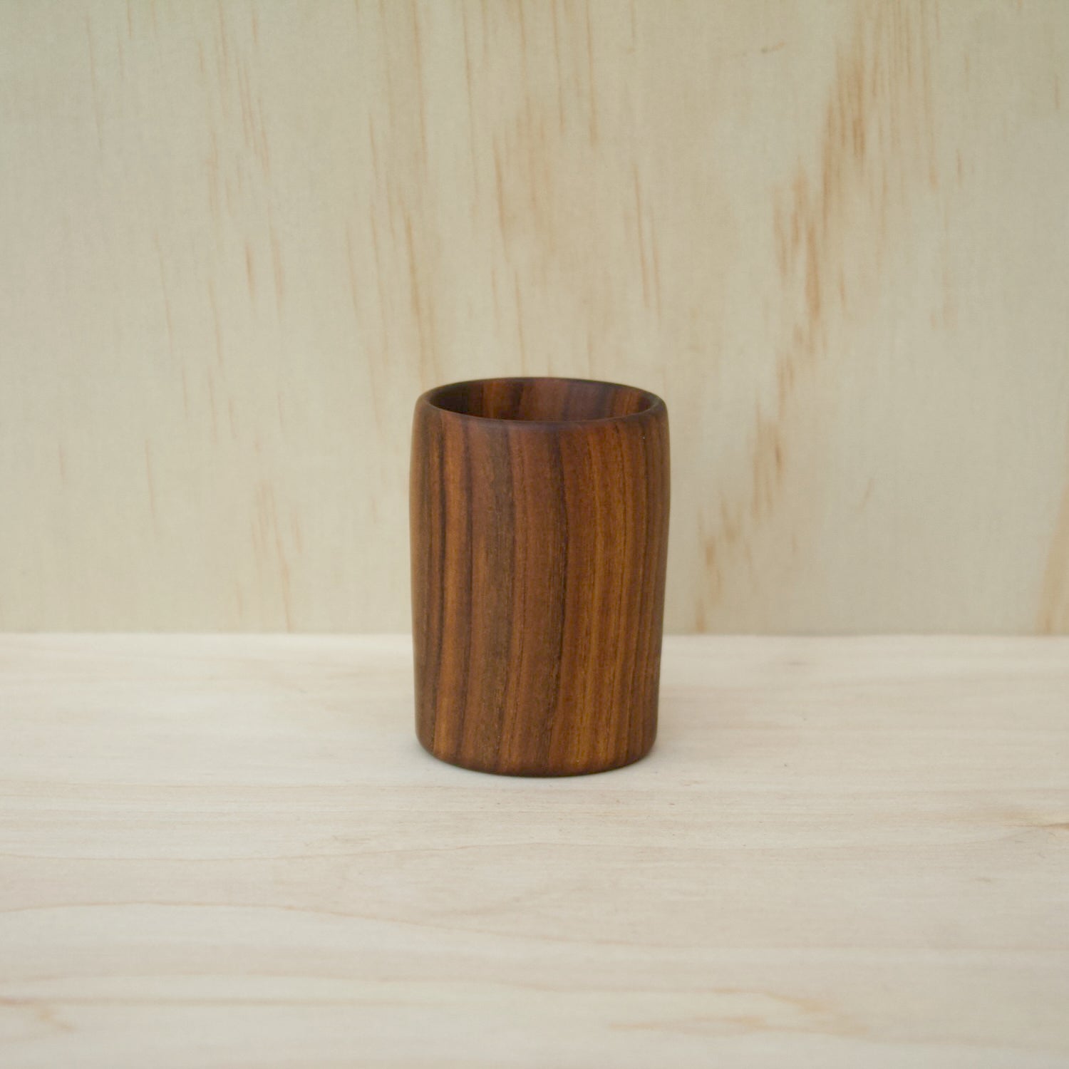 rich chocolate brown wooden cup on a light wooden surface. object made with red bud wood