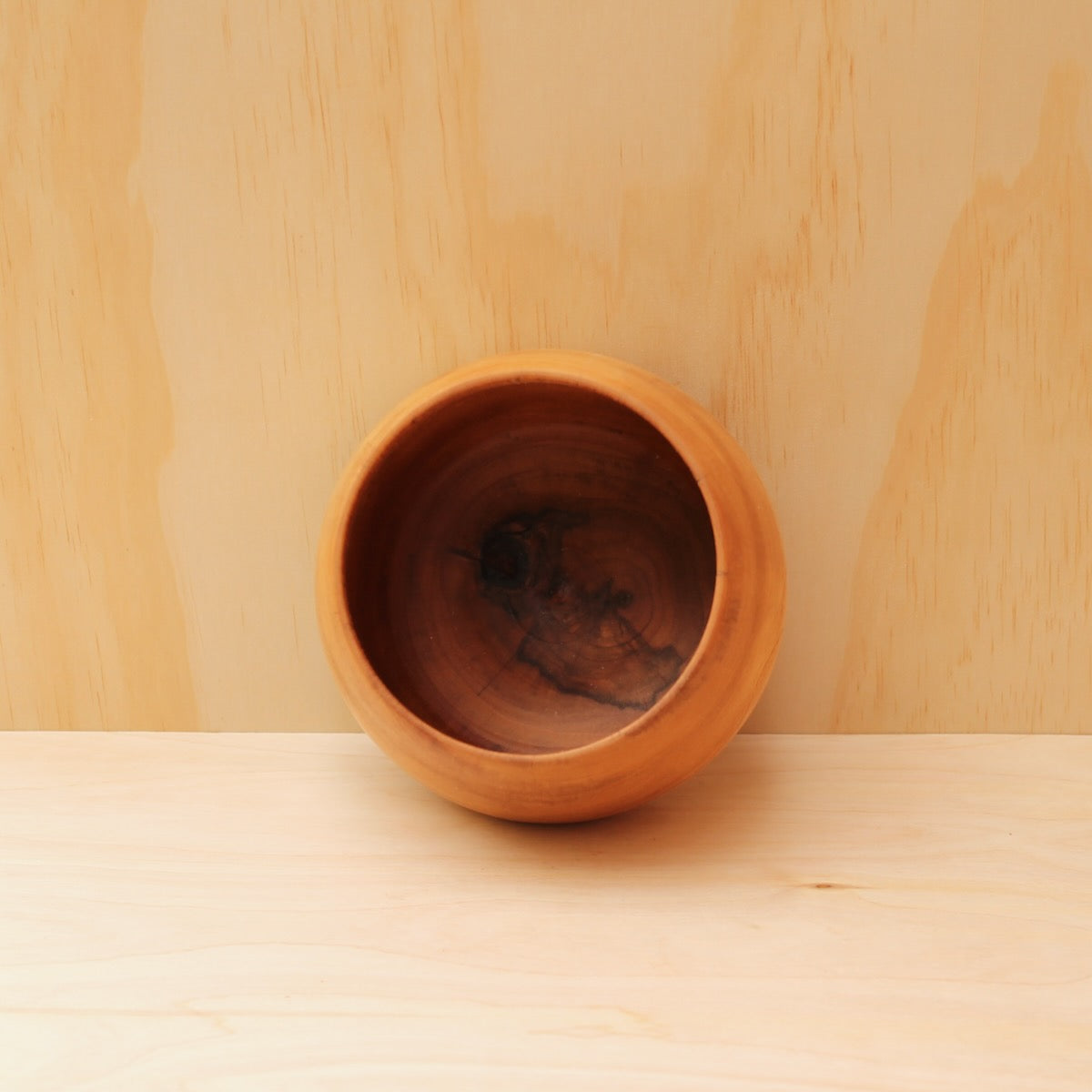 Wooden bowl on a wooden surface with a light wood panel background