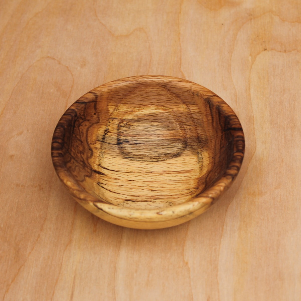 top of a wooden bowl made with rescued gran spalted oak on a light wooden surface