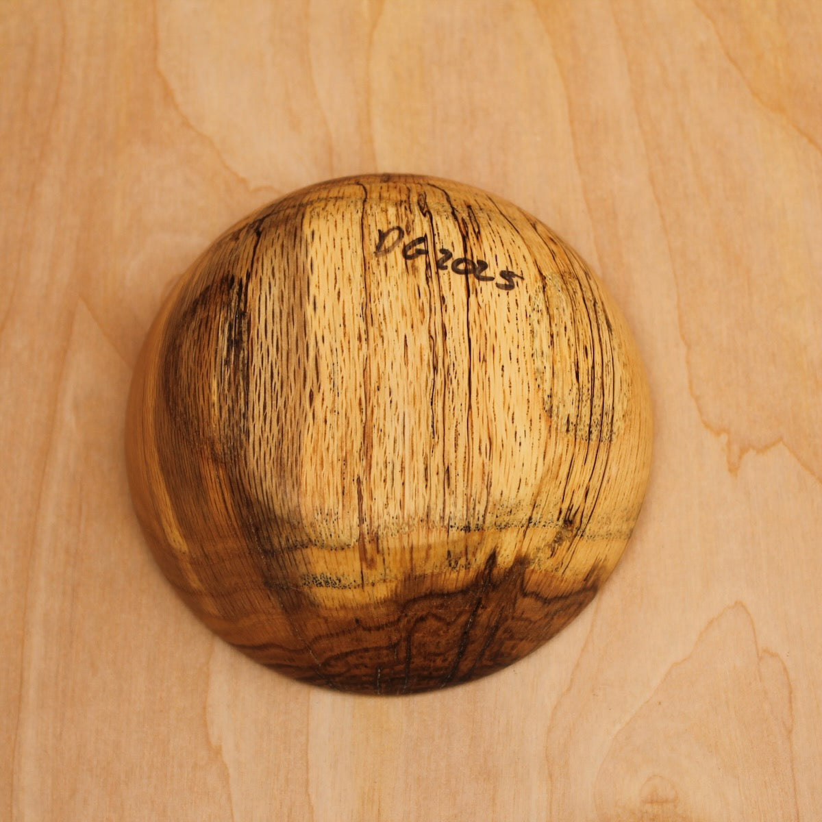 bottom of a wooden bowl made with rescued gran spalted oak on a light wooden surface