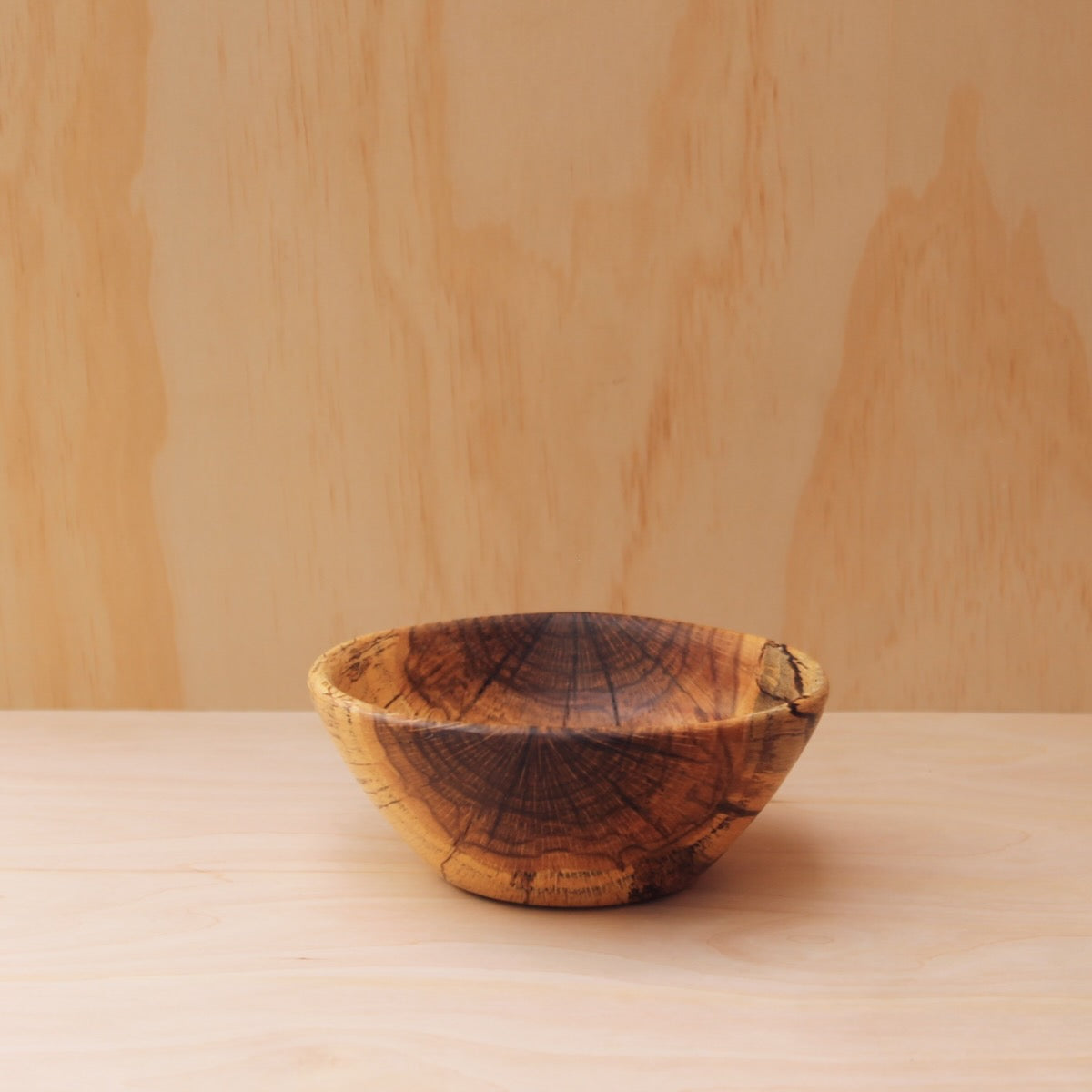 hand made wooden bowl made of rescued grain spalted oak on a light wooden background