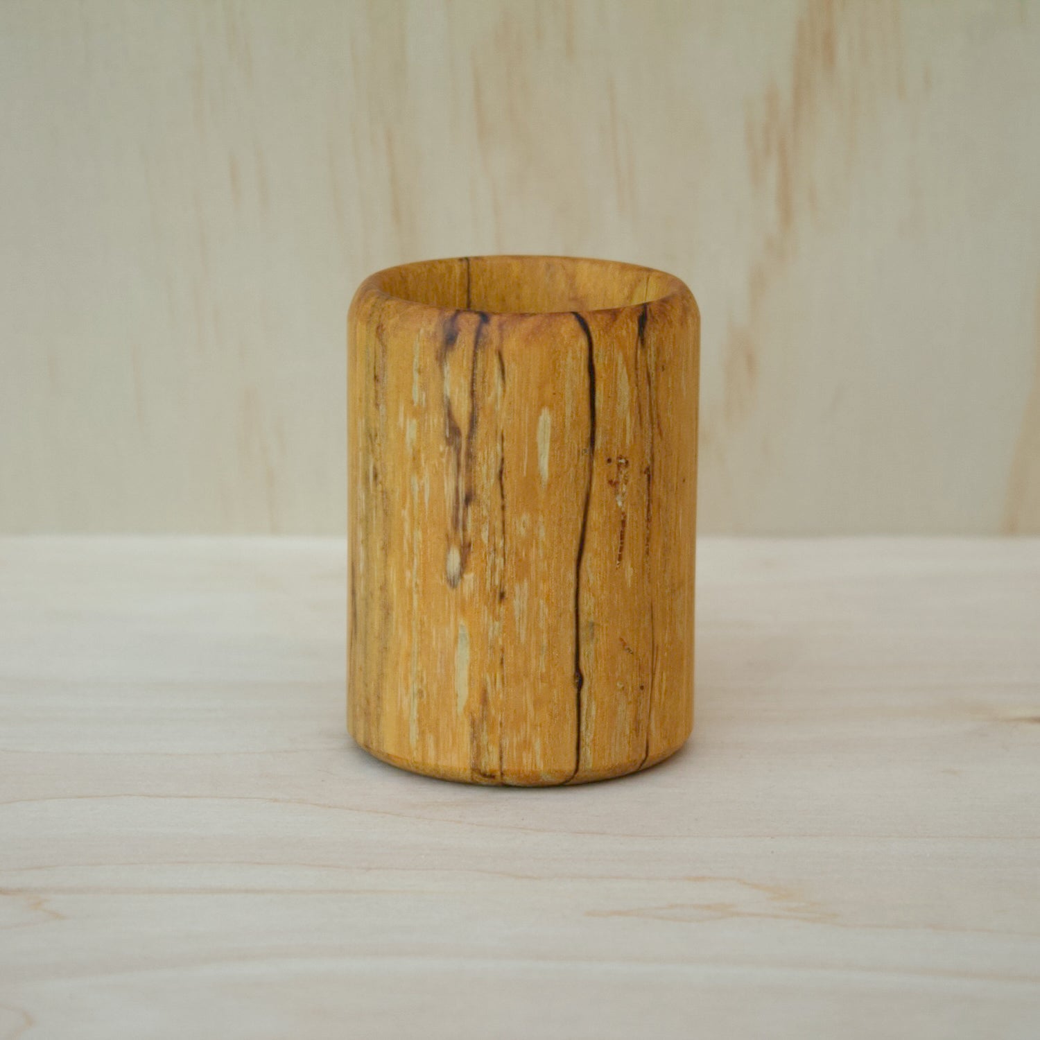 yellow wooden cup with back and white markings like a banana slug