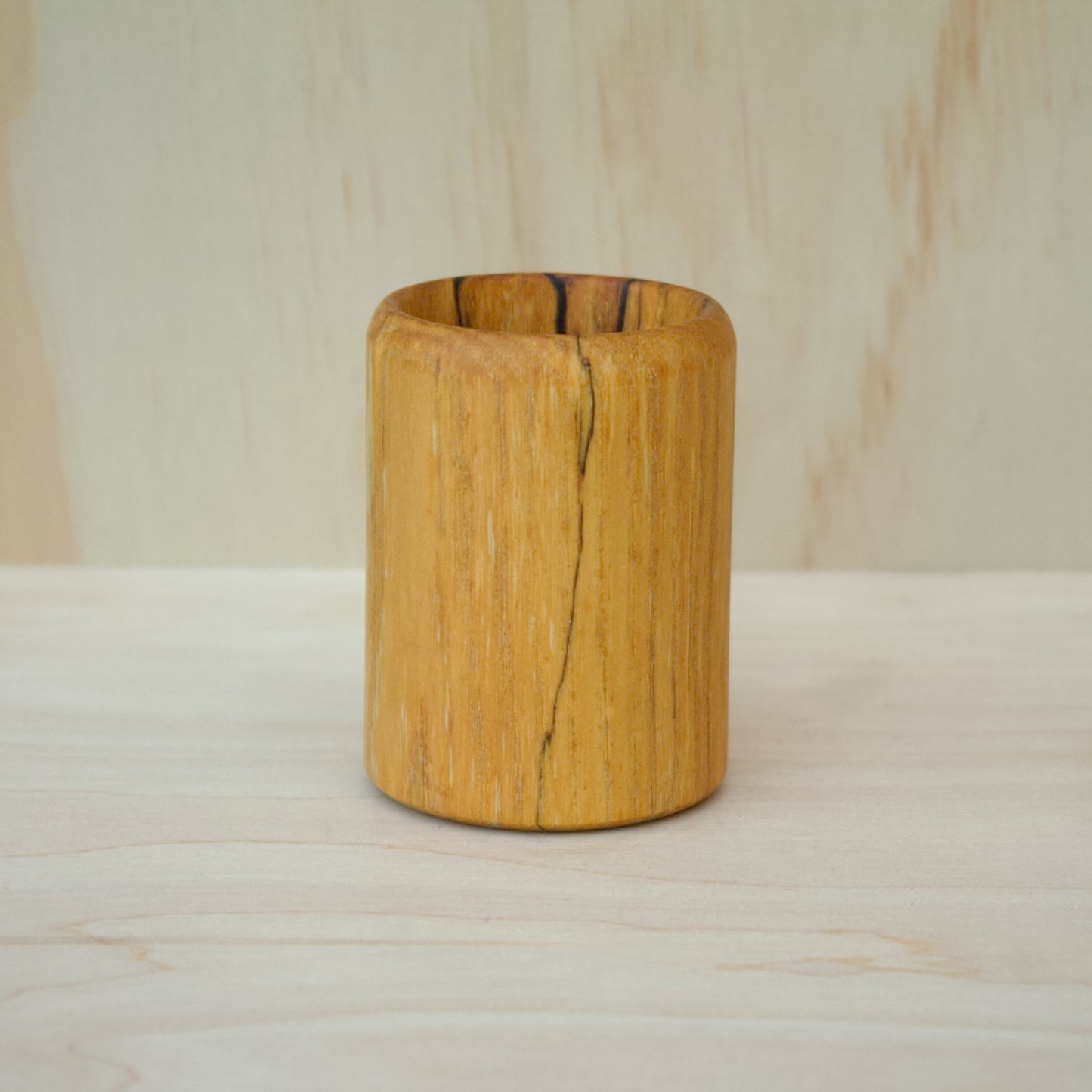 Wooden vase on a wooden surface with a neutral background