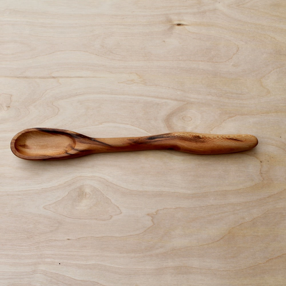 hand made wooden cooking spatula made with sycamore tree on a light wooden surface
