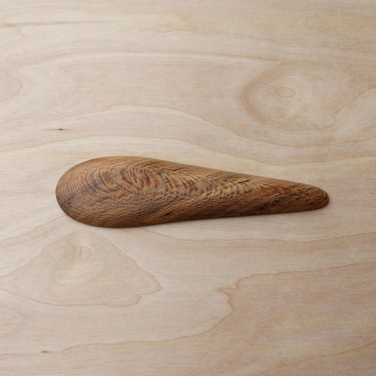 back of a wooden kayak spoon on a light wooden background
