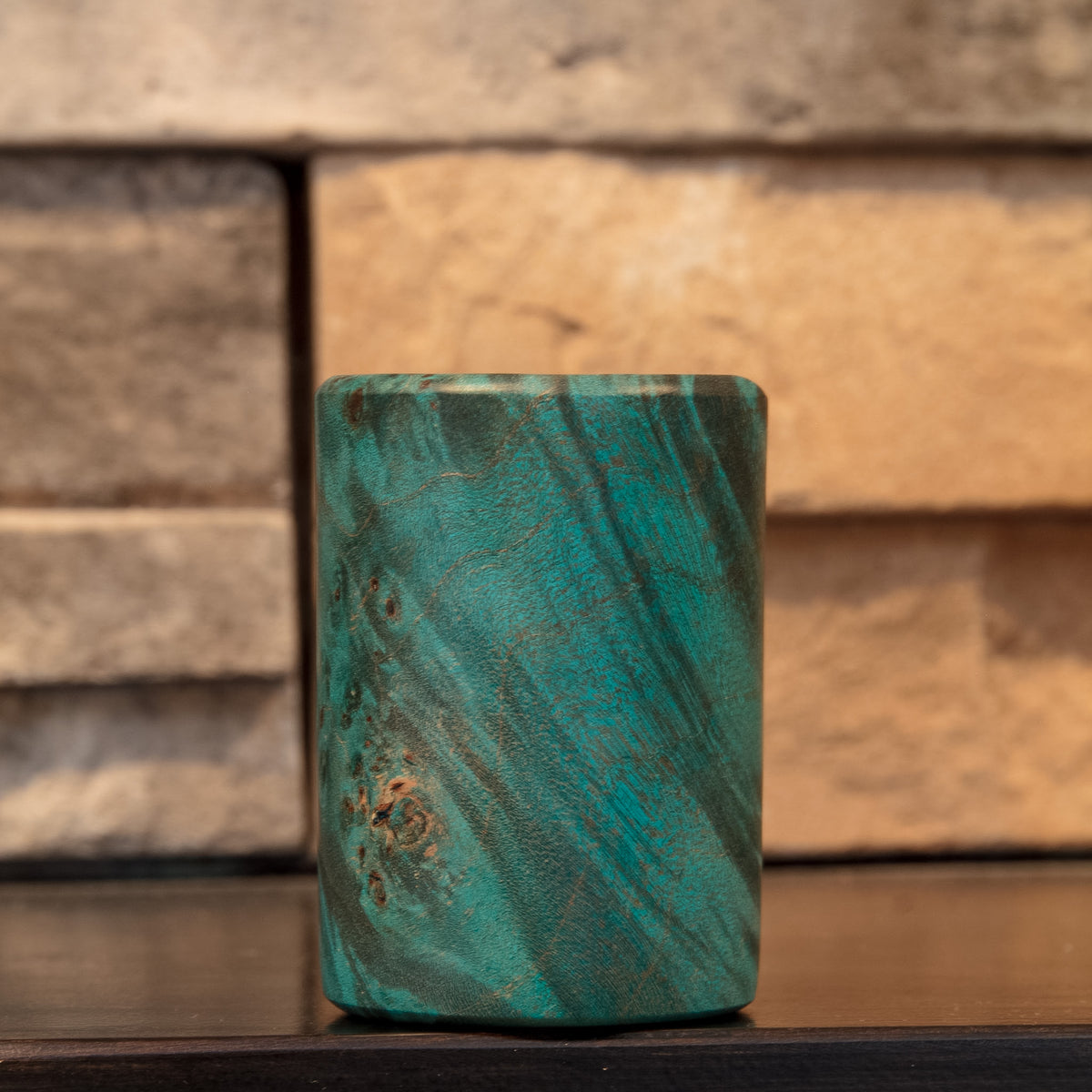 The Forgotten Current Mappa Burl shot glass showing clustered natural burl eyes through turquoise-green figure
