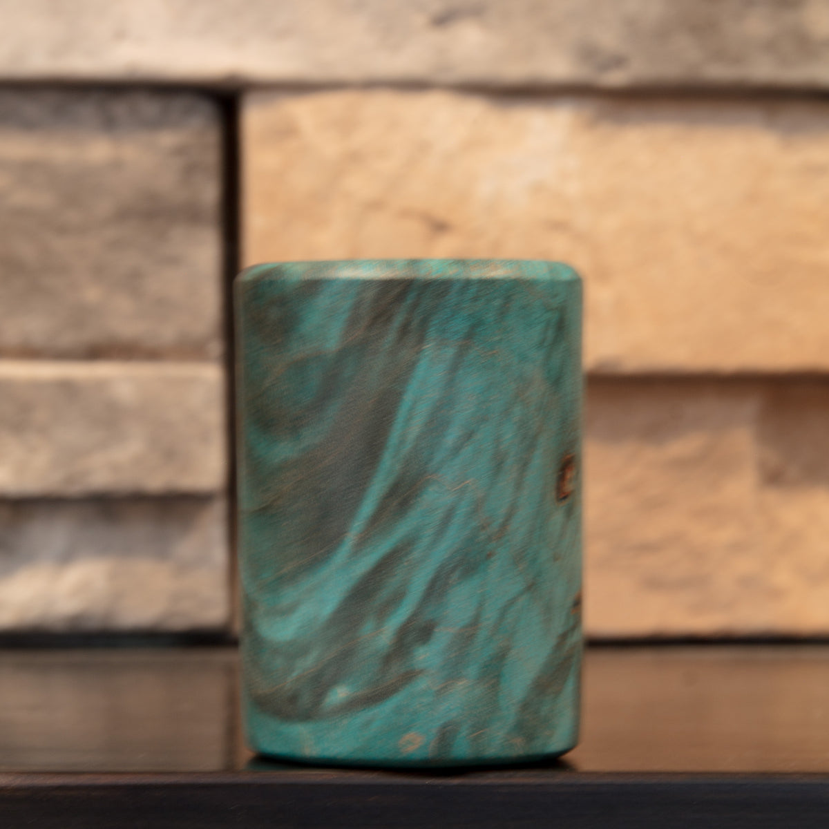 The Forgotten Current shot glass showing broad curved dark figure through green-dyed Mappa Burl