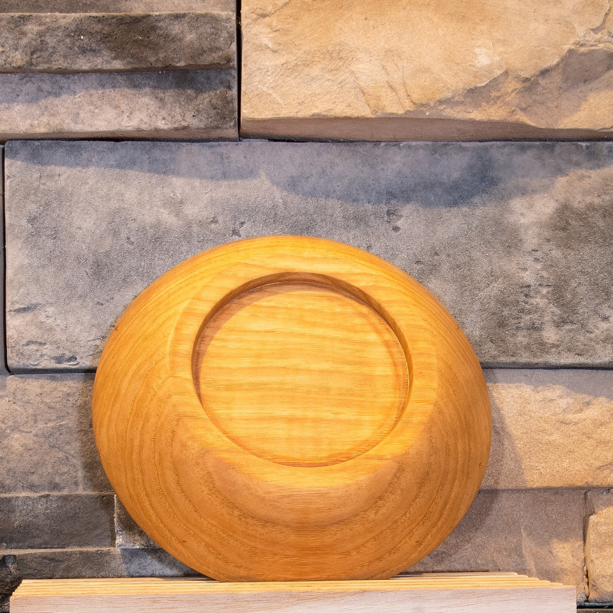 Underside of The Patient Grain pecan bowl showing the recessed circular foot and concentric exterior grain