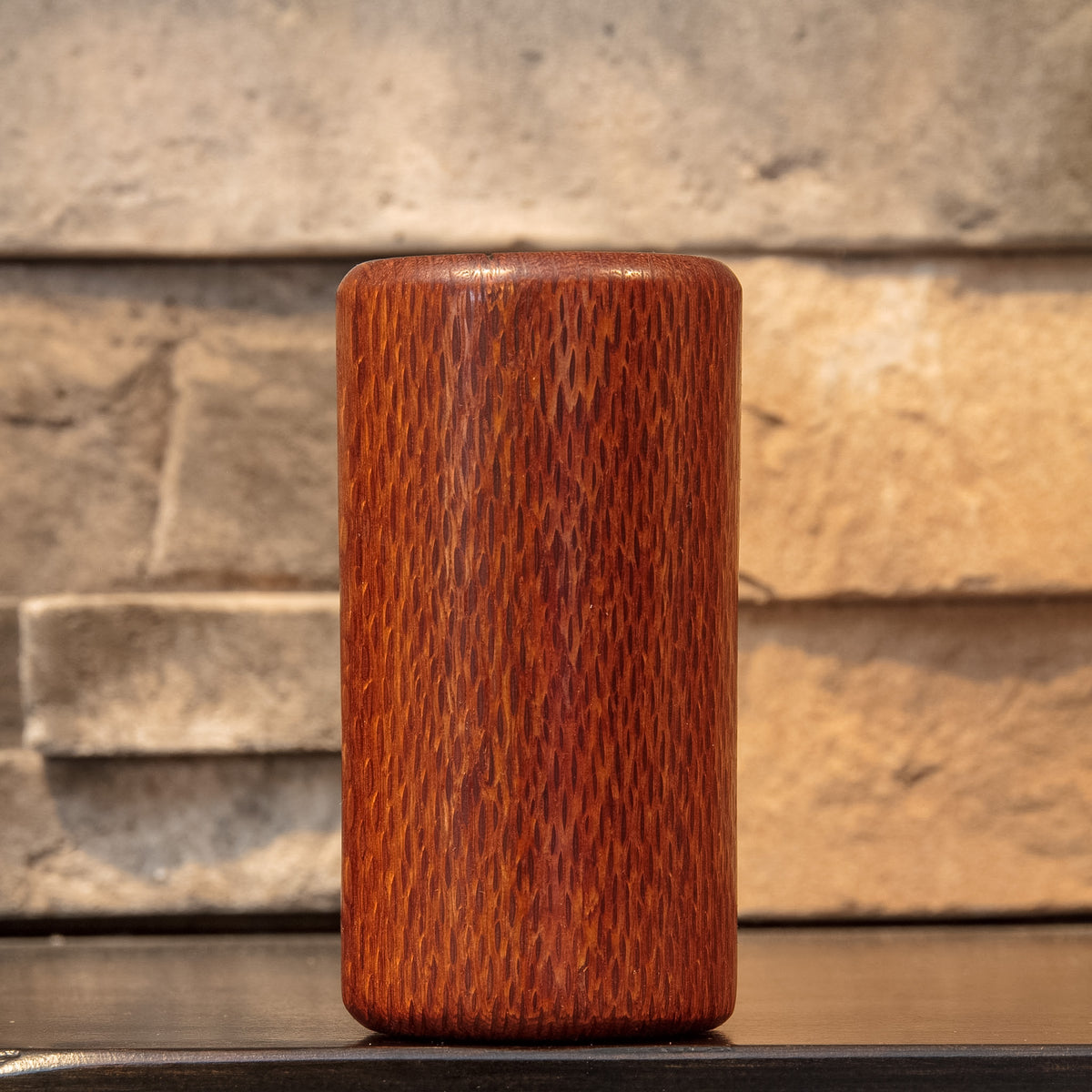 The Spotted Stalk leopardwood shot glass rotated to show dense elongated grain figure across its reddish-brown exterior.