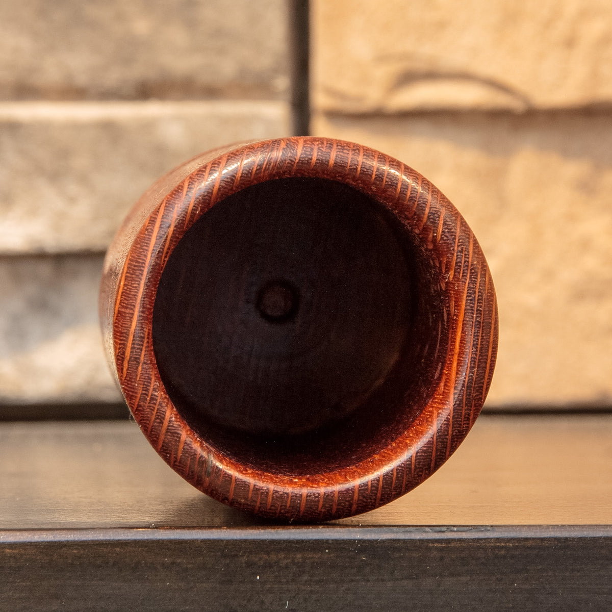 Top view into The Spotted Stalk leopardwood shot glass, showing its dark hollow interior and rounded figured rim.