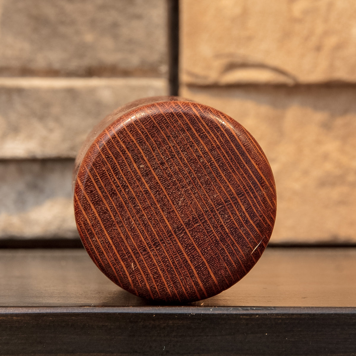 Bottom view of The Spotted Stalk leopardwood shot glass, showing closely spaced dark end grain crossed by narrow lighter rays.