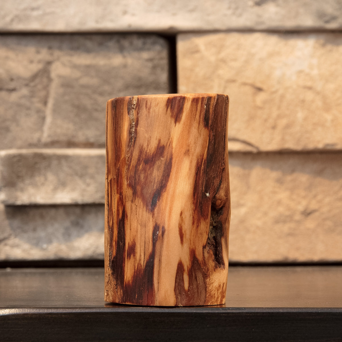 Angled view of The Wild Branch cottonwood shot glass highlighting varied dark heartwood-like streaks and a natural recessed branch feature.