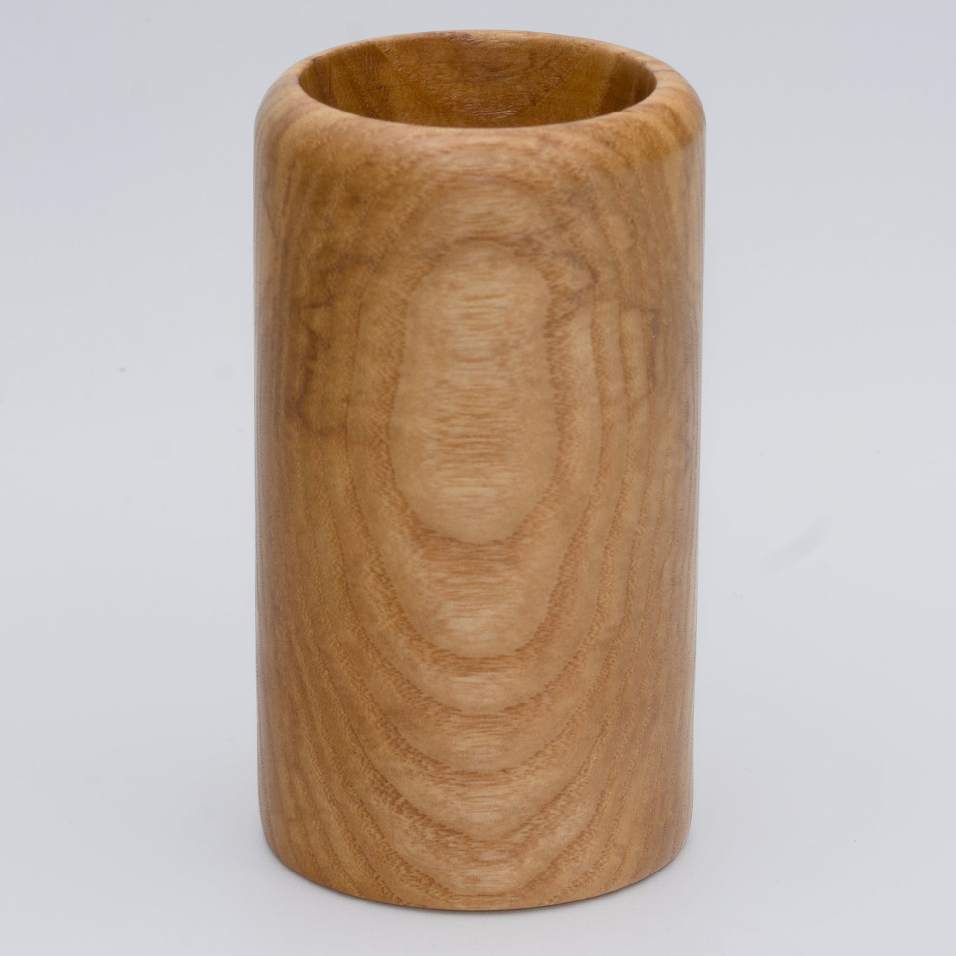 Figured ash wood shot glass against white background