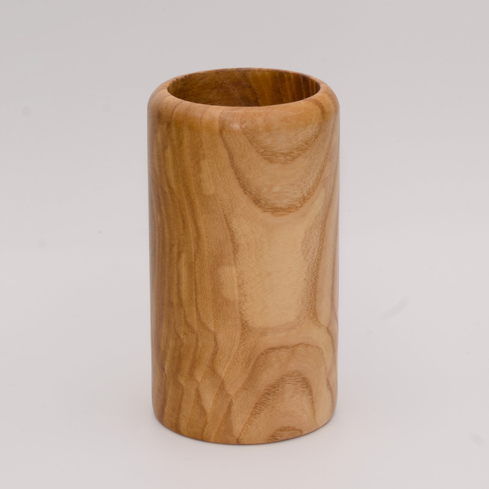 Figured ash wood shot glass against white background
