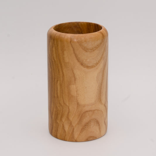 Figured ash wood shot glass against white background