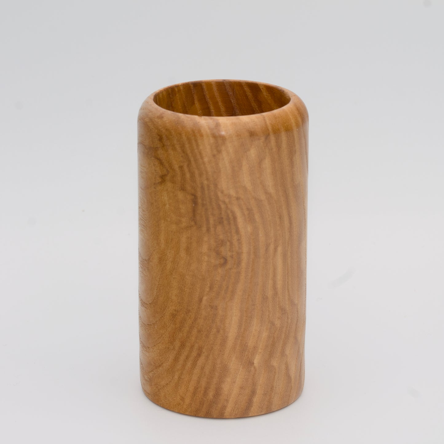 Figured ash wood shot glass against white background