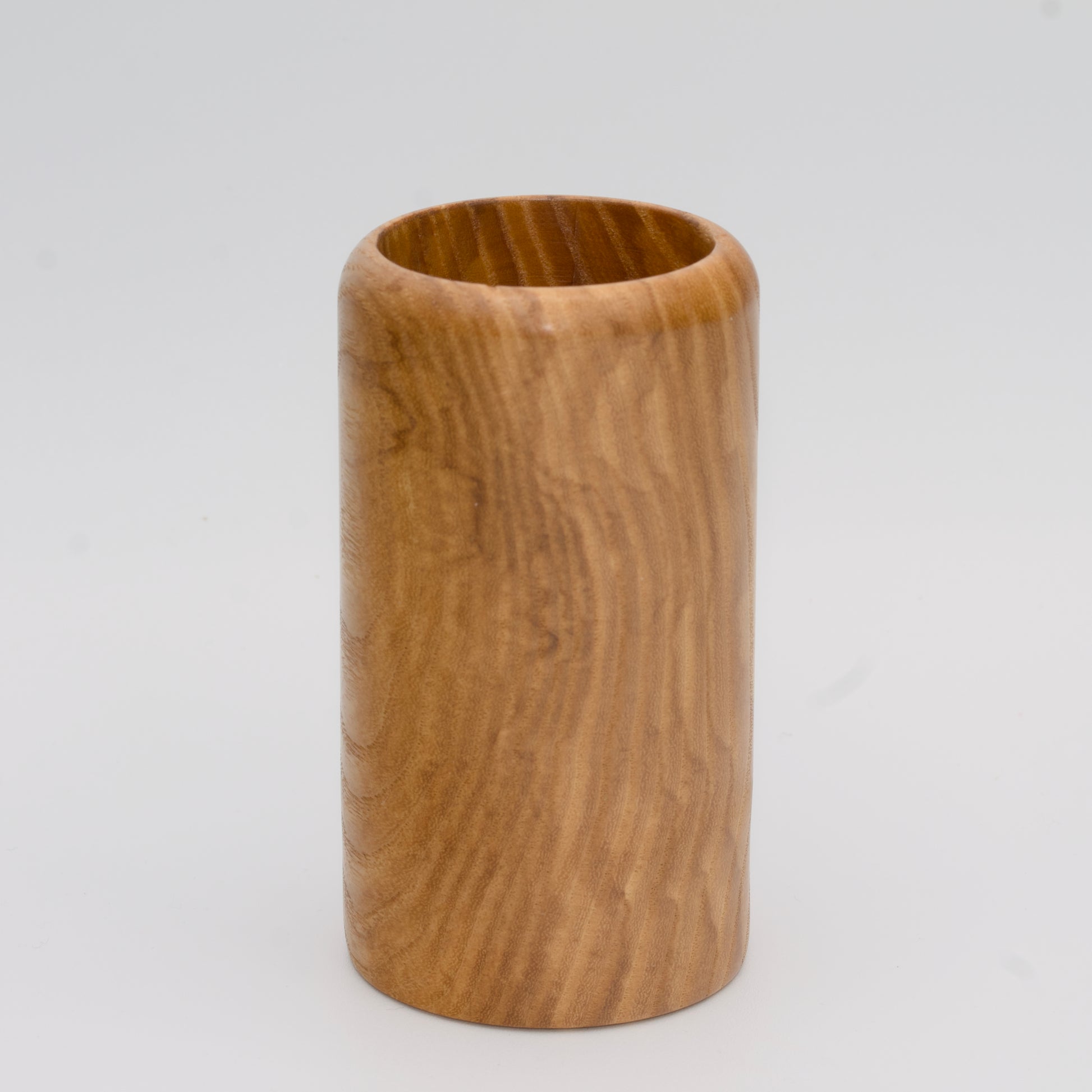 Figured ash wood shot glass against white background