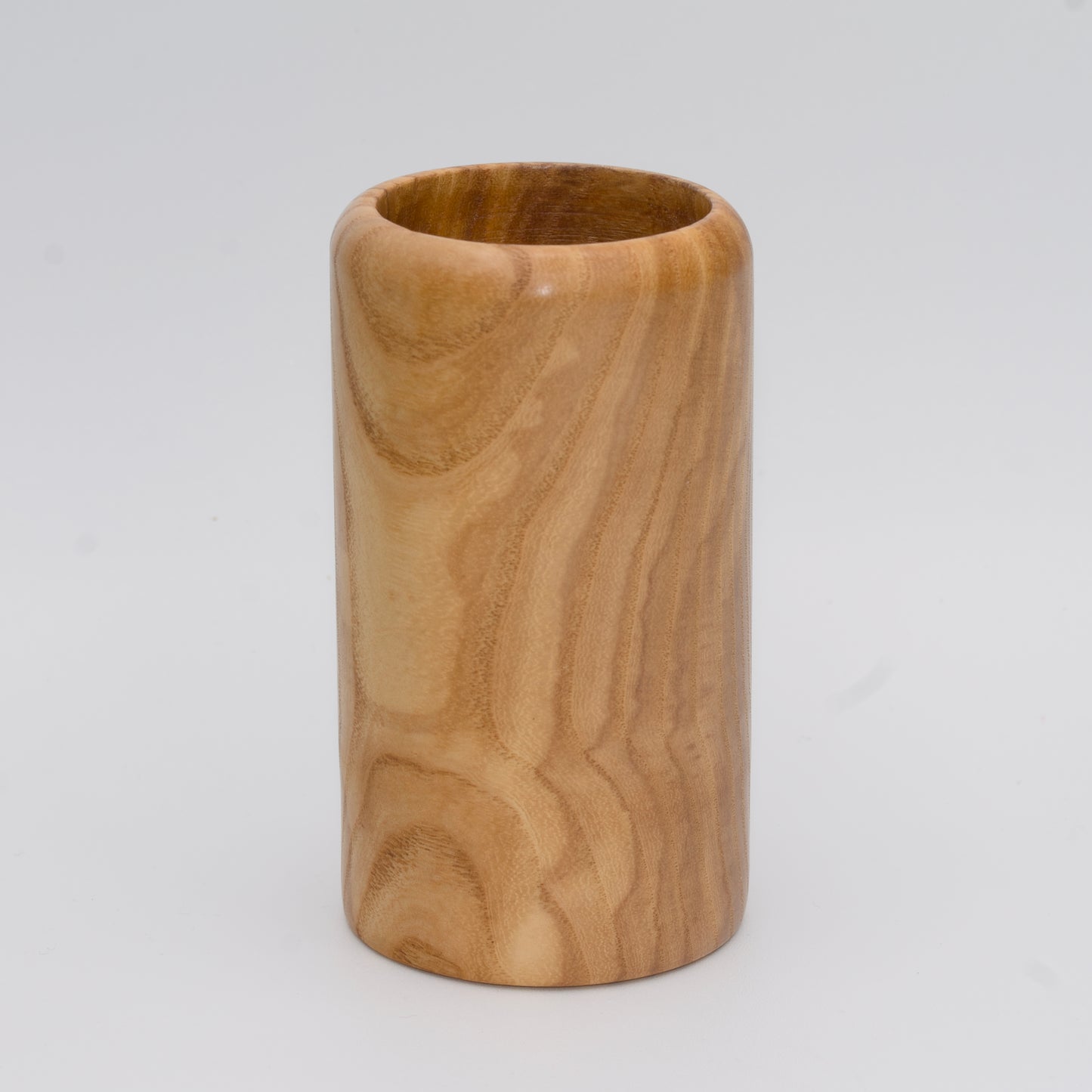 Figured ash wood shot glass against white background