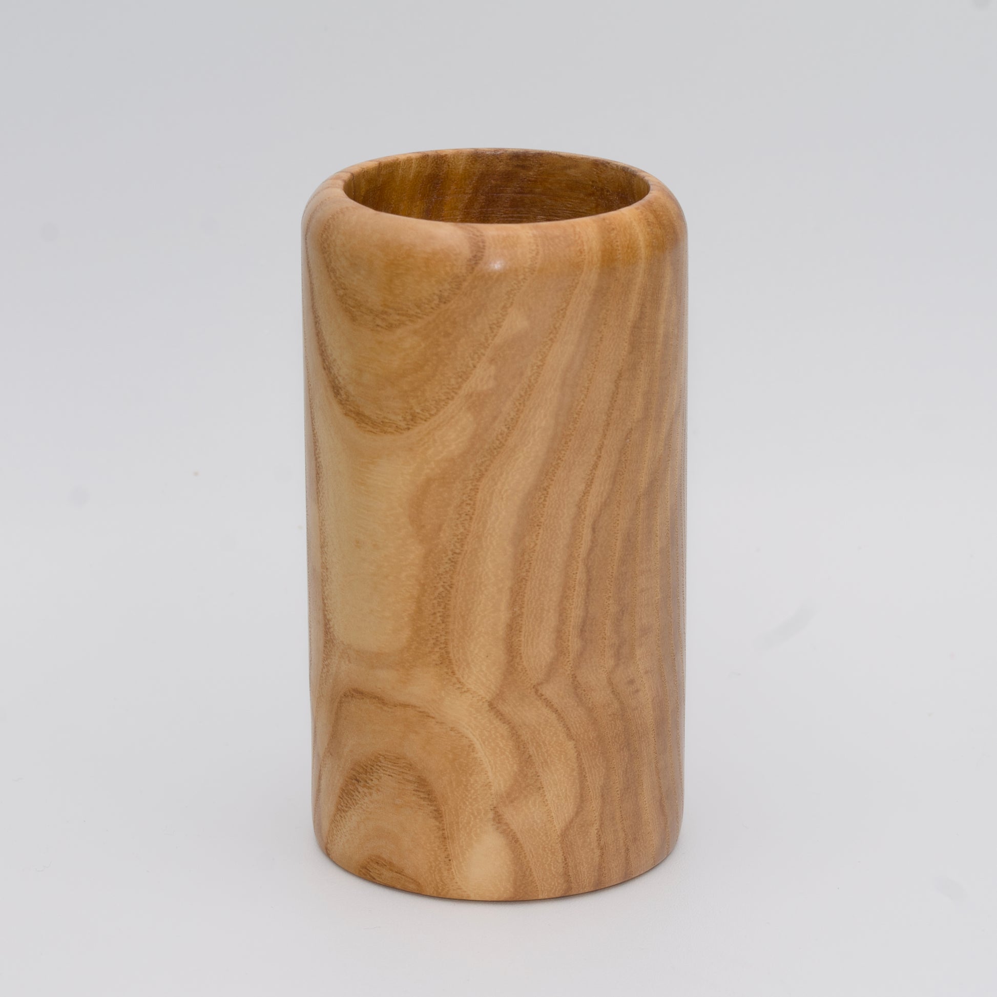 Figured ash wood shot glass against white background