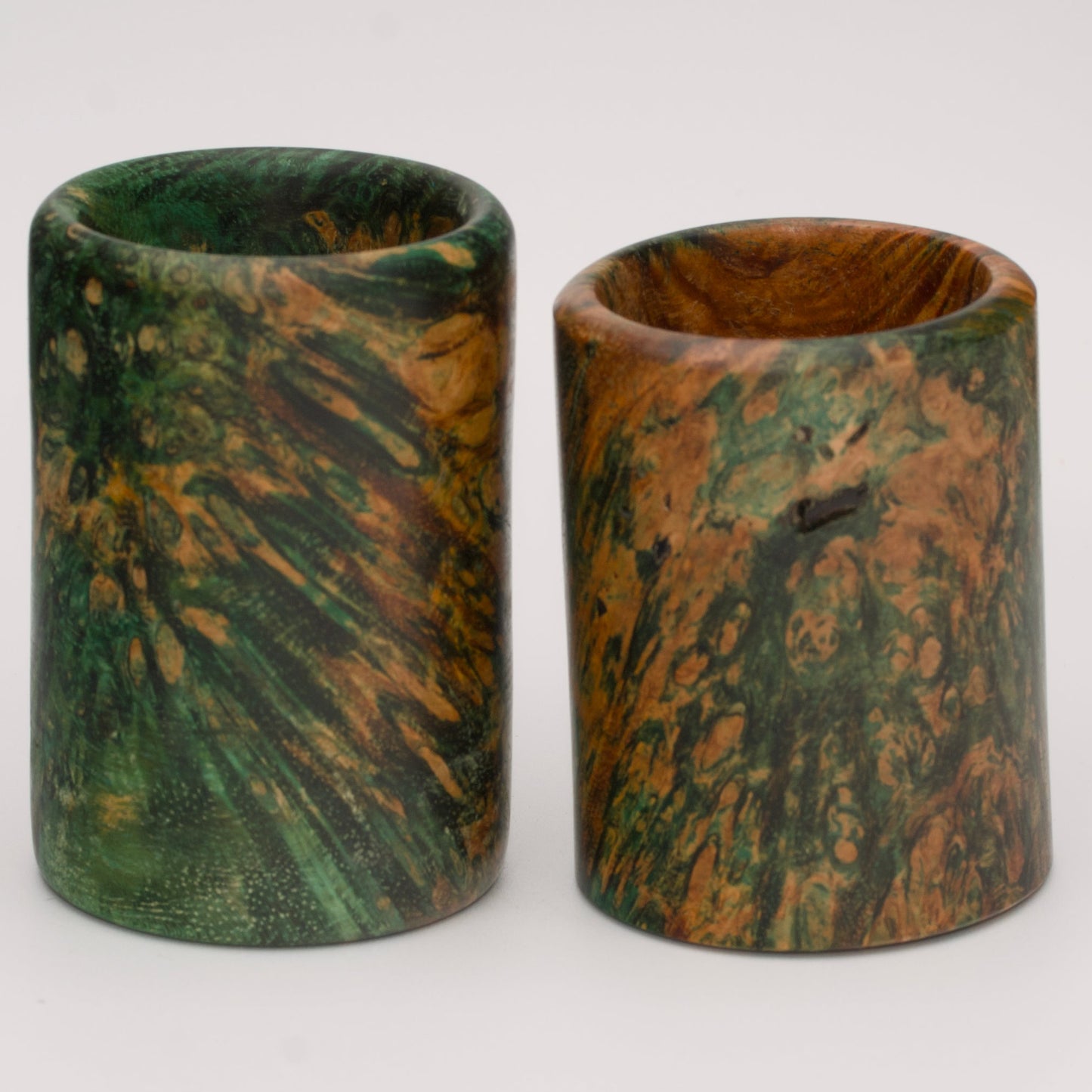 Pair of dyed green river tamarind burl shot glasses against white background