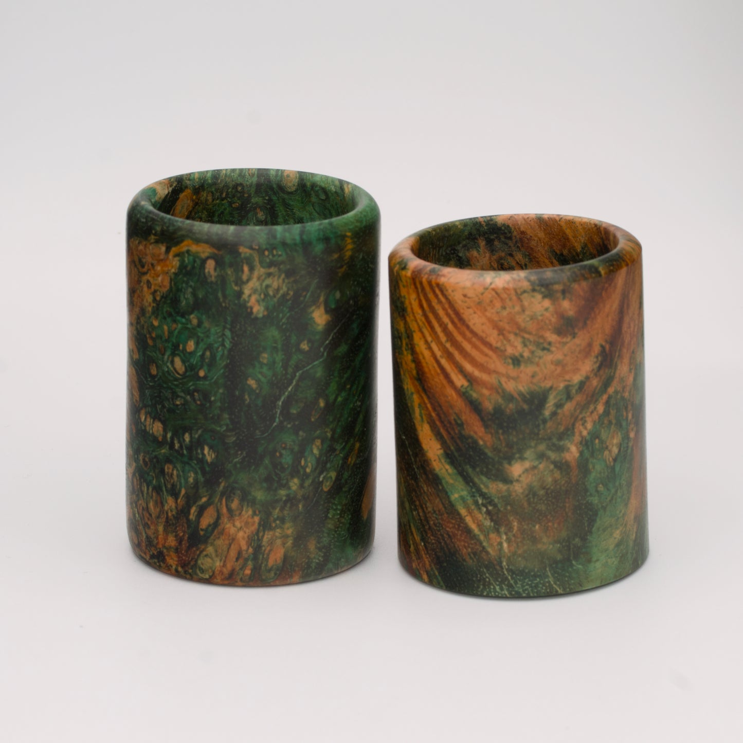 Pair of dyed green river tamarind burl shot glasses against white background