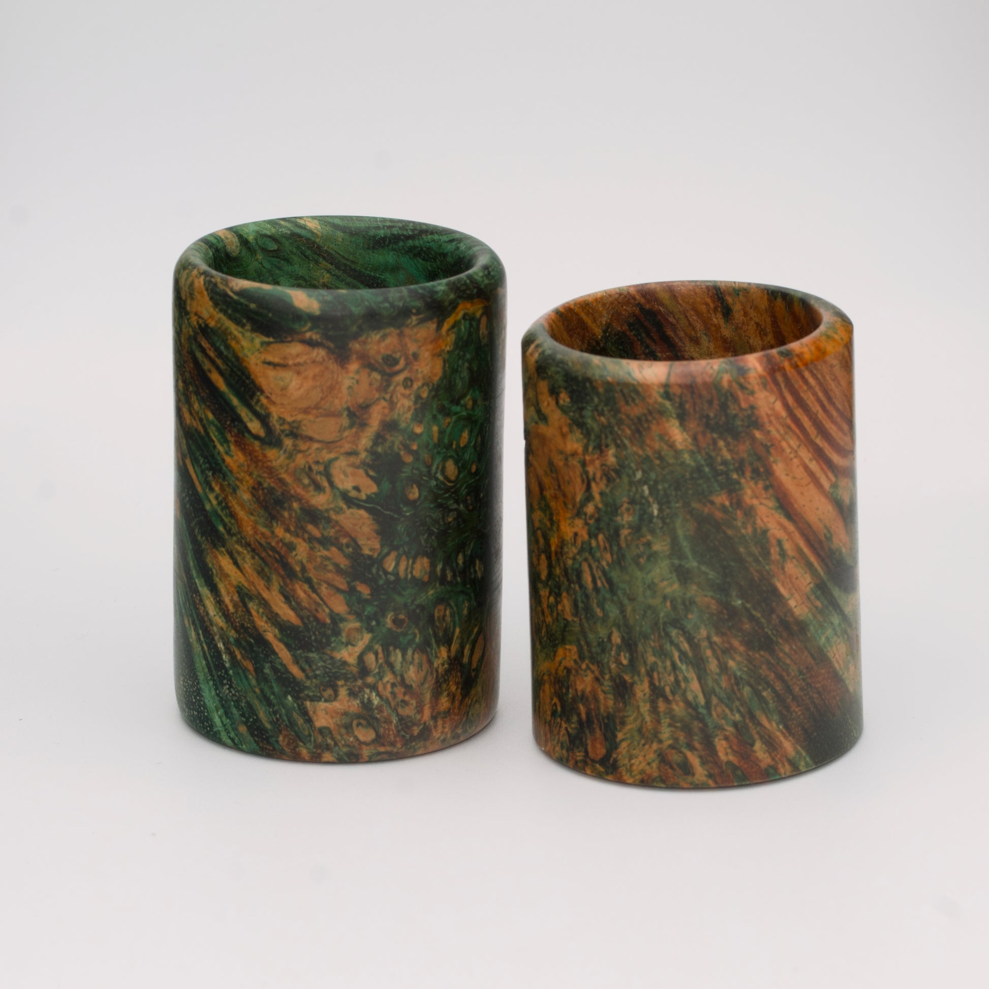 Pair of dyed green river tamarind burl shot glasses against white background