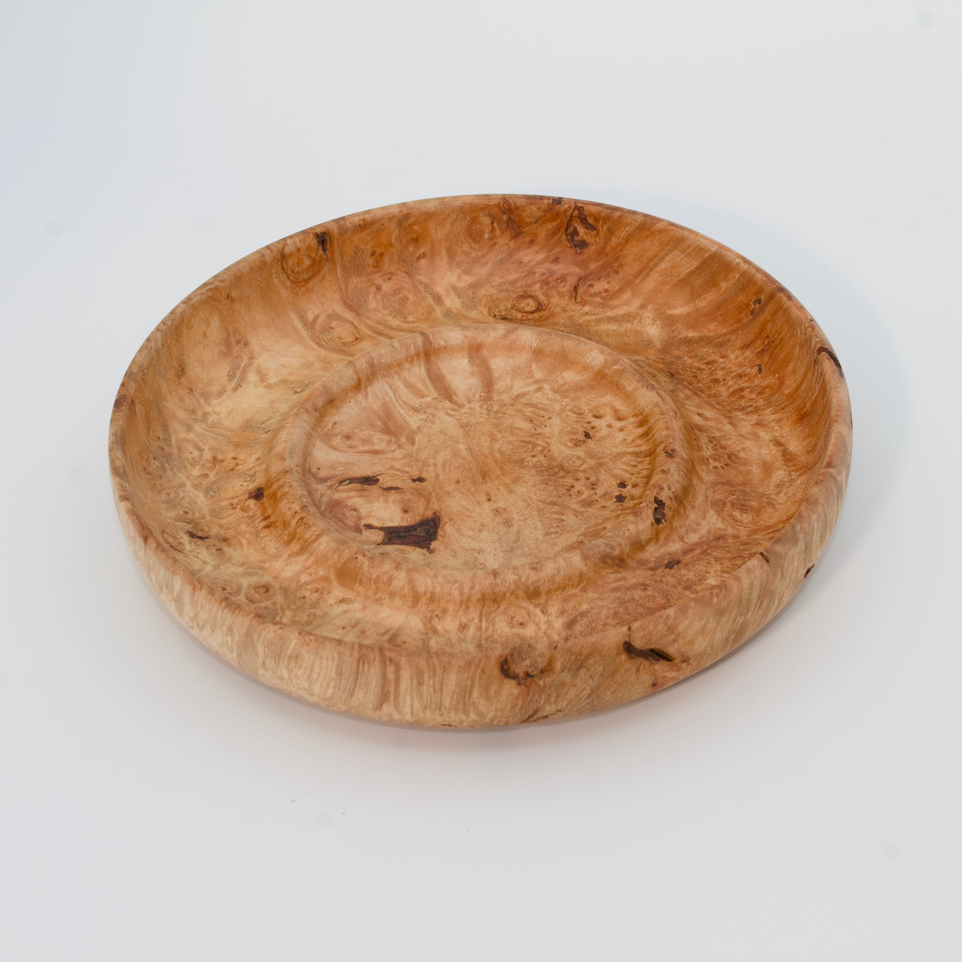 Decorative wooden plate from big leaf maple burl on a white background
