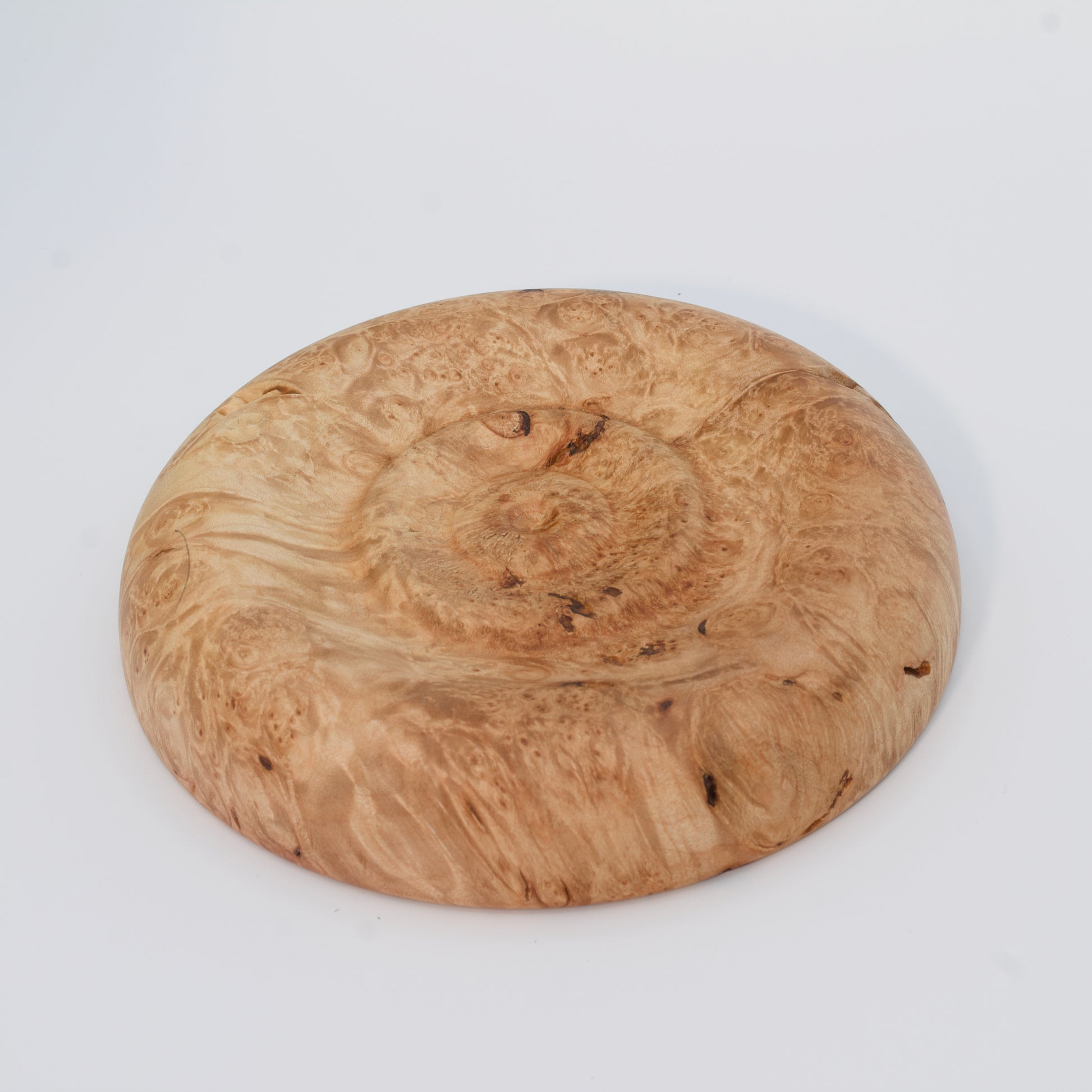 Decorative wooden plate from big leaf maple burl on a white background