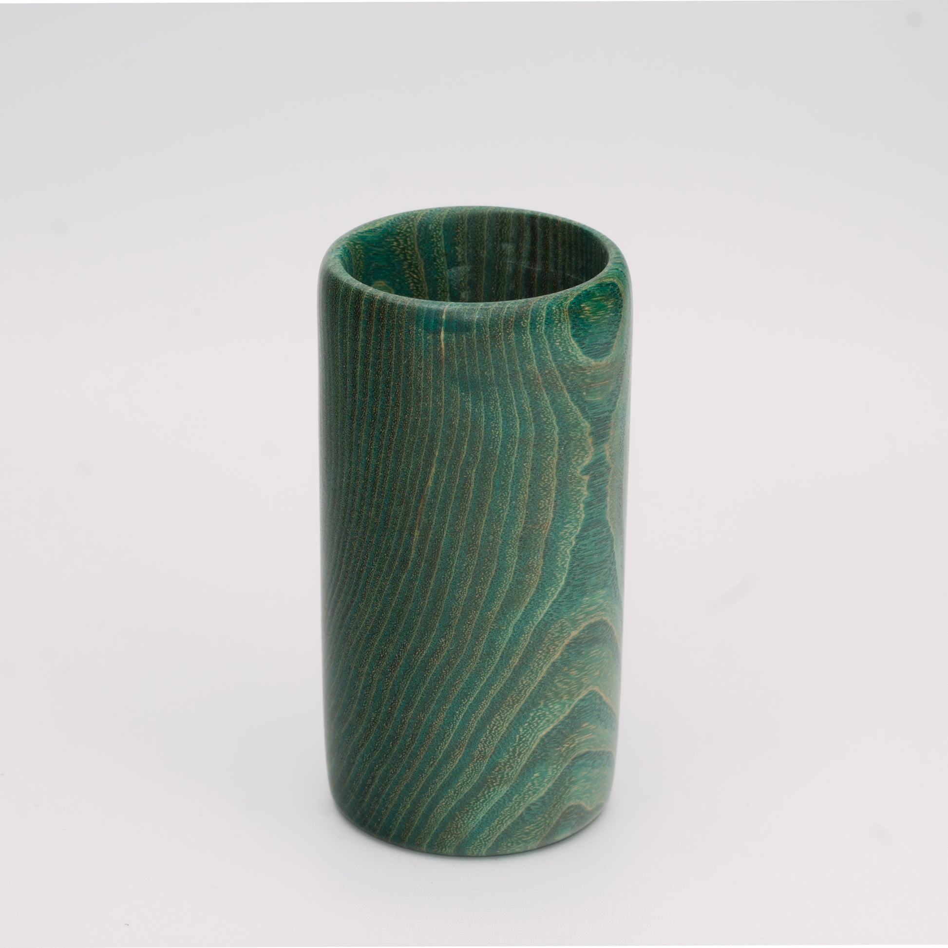 Green dyed oak wood shot glass against white background