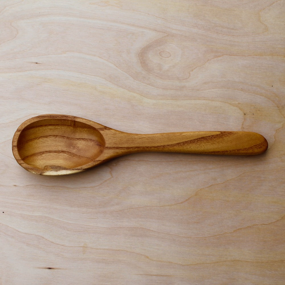 hand made wooden spatula with dark brown stripes on a light wooden surface