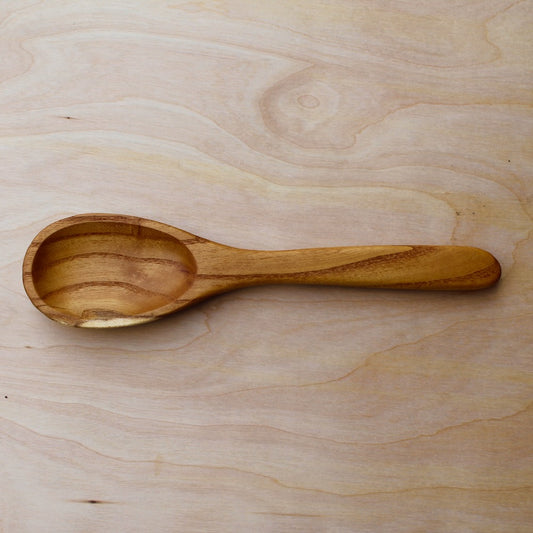 hand made wooden spatula with dark brown stripes on a light wooden surface