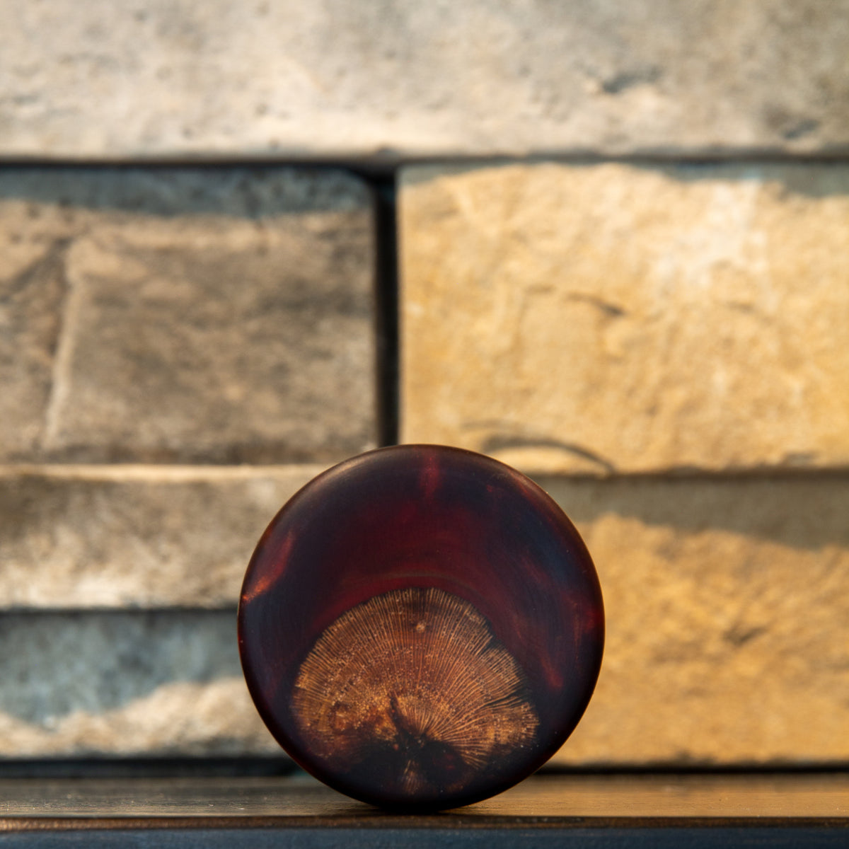 Bottom view of grapevine and wine-red resin shot glass showing fan-shaped radial end grain beneath burgundy-red resin