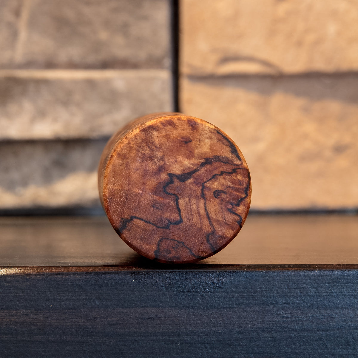 Bottom view of The Long Game showing warm Bigleaf Maple burl end grain crossed by dark spalting