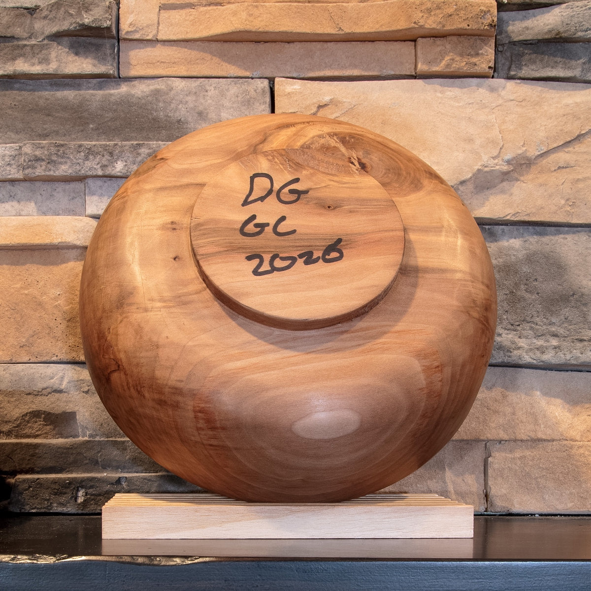 Underside of The Next Turn Sweetgum bowl showing the turned foot, varied grain, and DG GC 2026 maker mark 