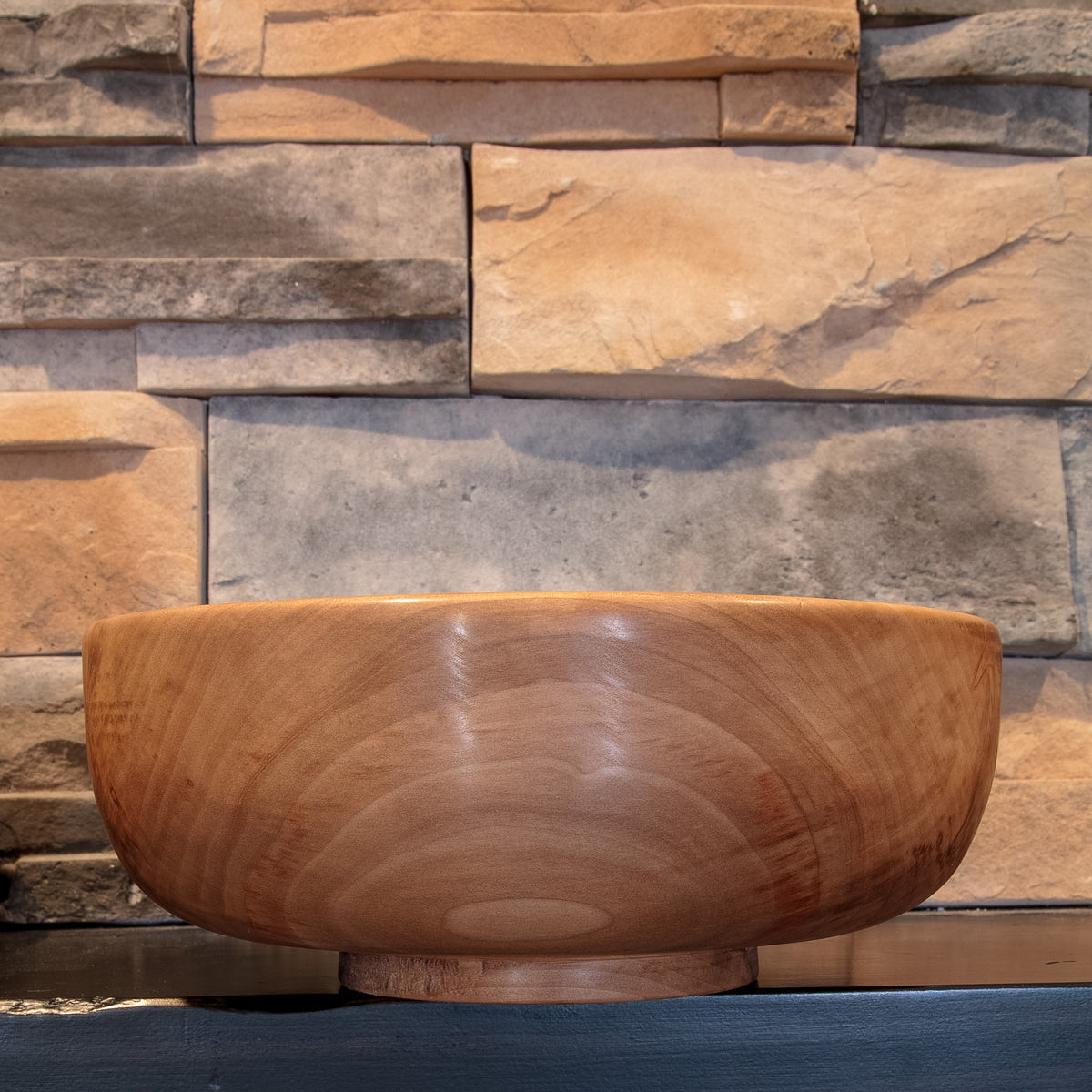 The Next Turn Sweetgum serving bowl showing its broad rounded form, raised foot, and sweeping warm grain
